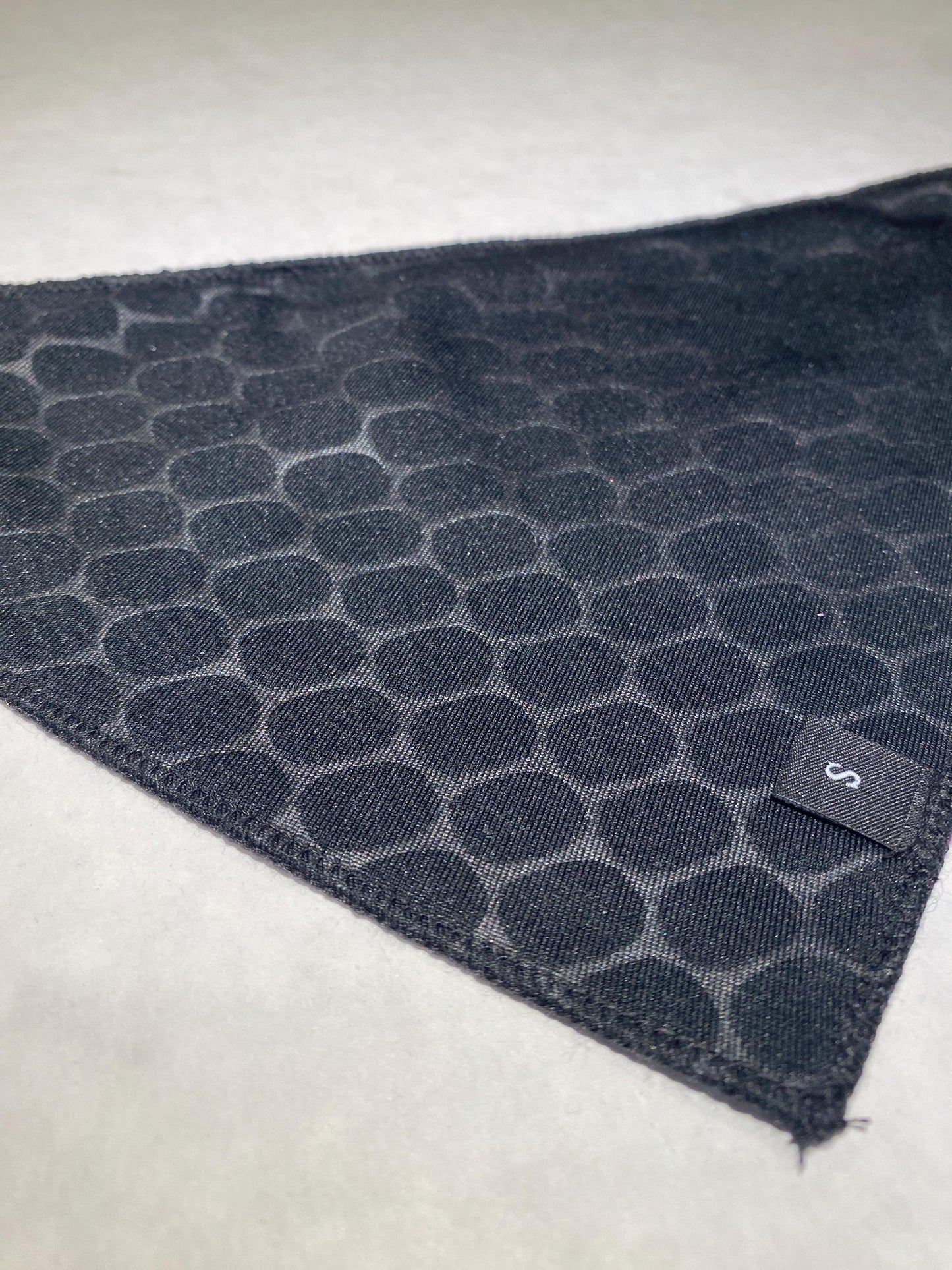Black lining of the backside of a dog bandana with a size label.