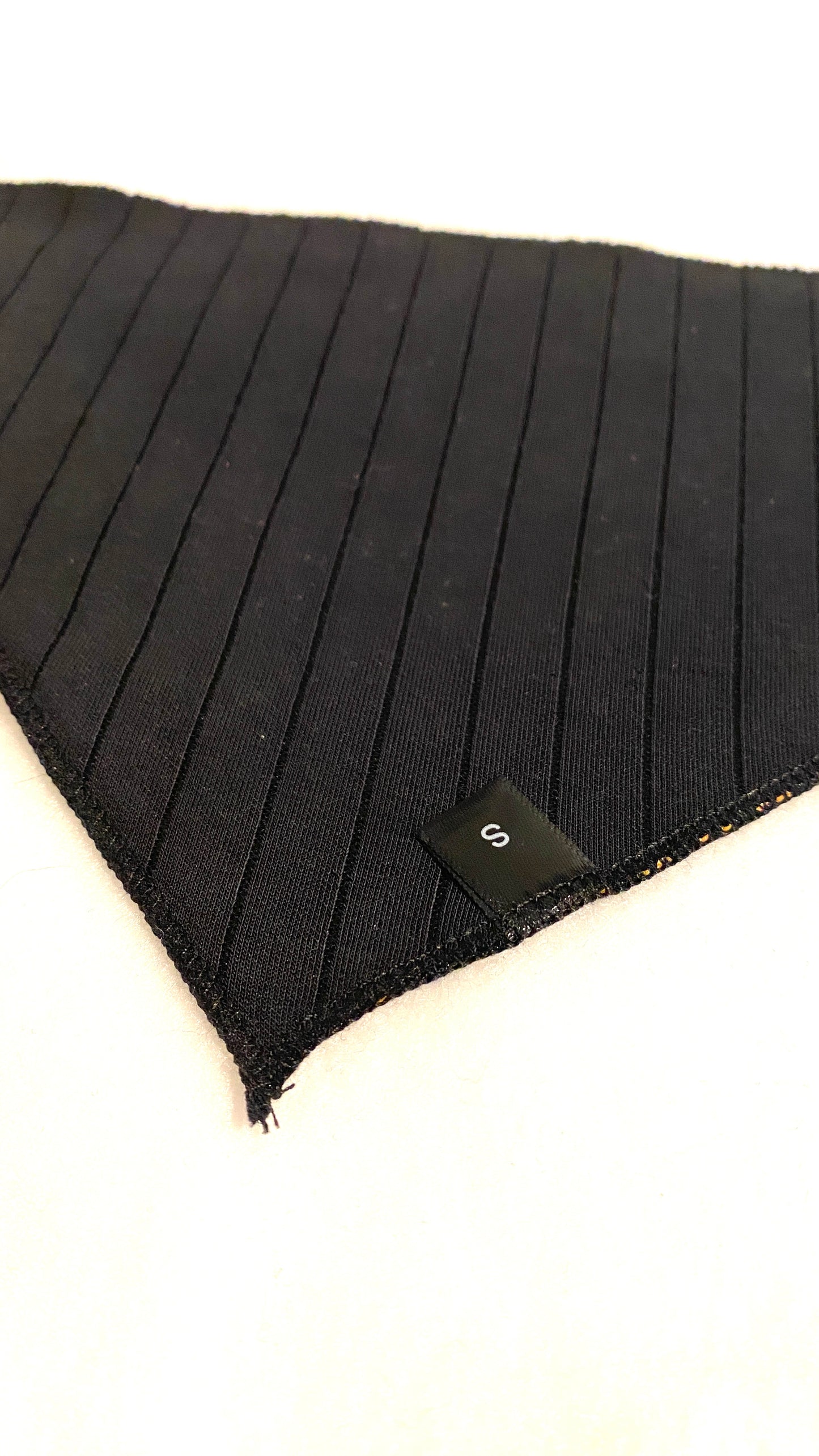 Black backing of a dog bandana with a size label on a white background