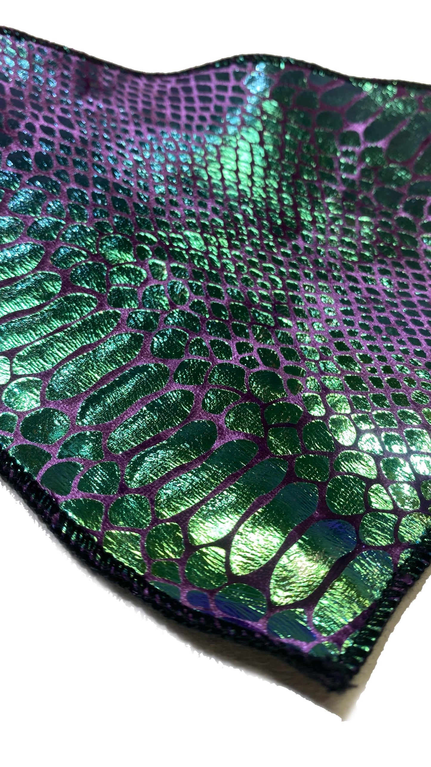A closeup of a green and purple velvet snake skin pattern bandana with a shiny, metallic finish.