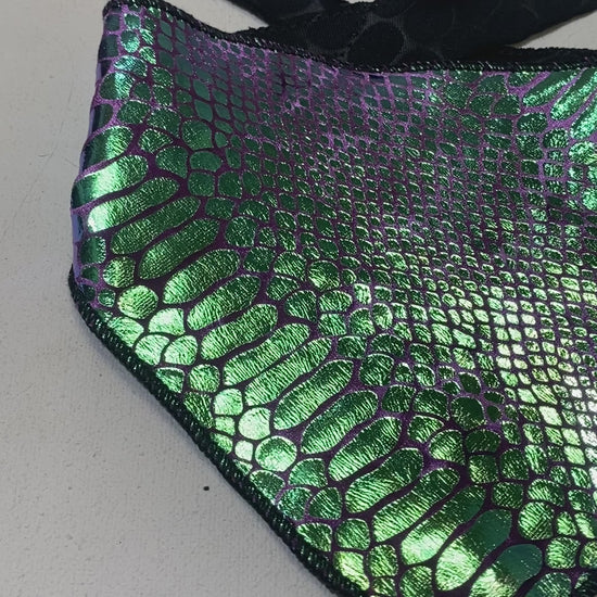 A video of a green and purple velvet snake skin pattern bandana with a shiny, metallic finish and black ties.