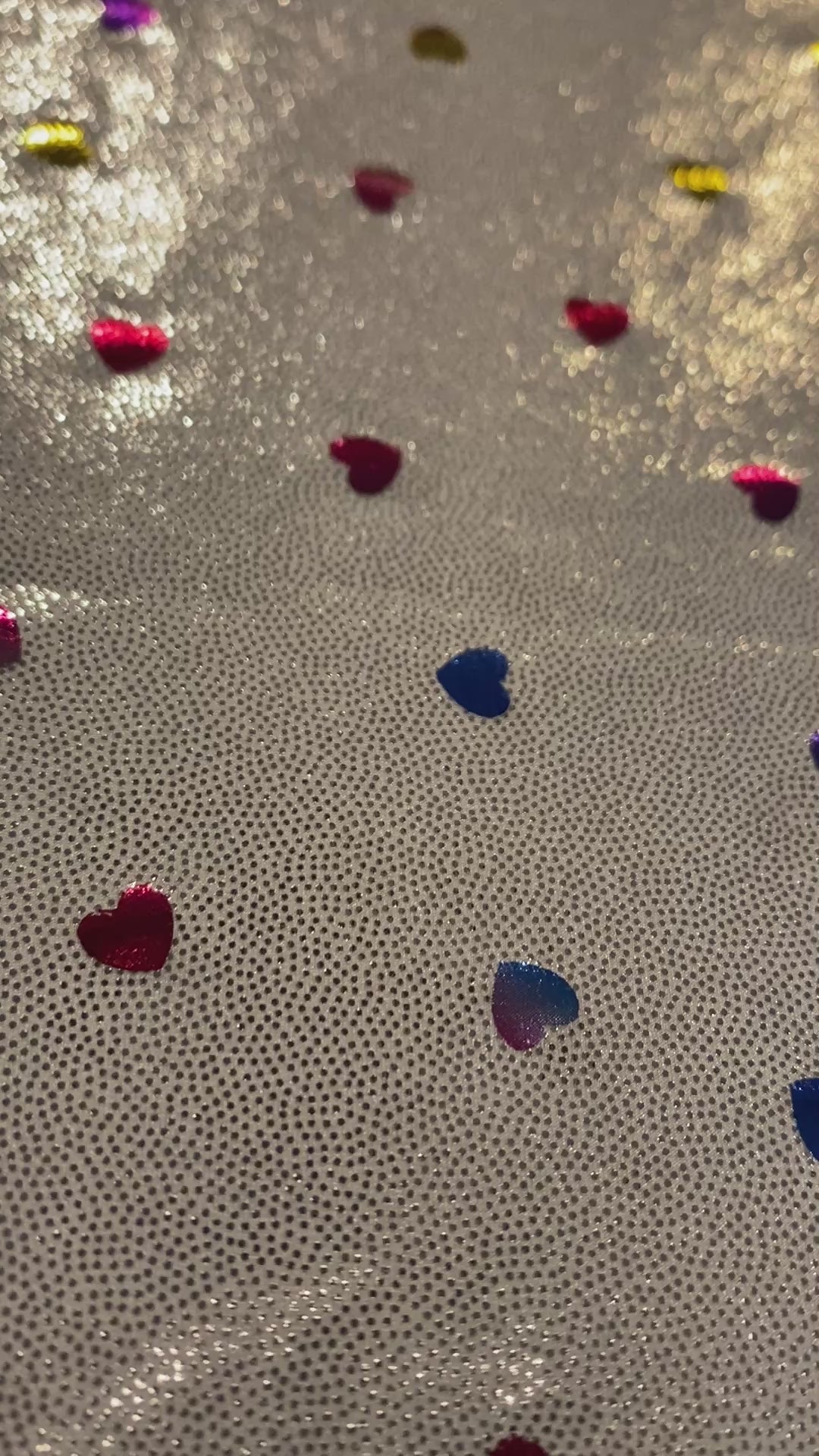 Video of metallic silver fabric with multicolored metallic hearts.